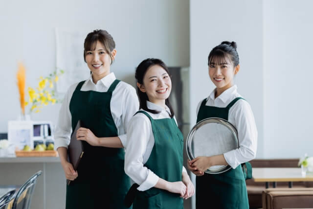 カフェでエプロンを着た三人のスタッフ