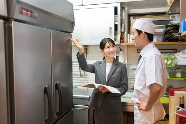 厨房で冷蔵庫を指差すビジネスウーマン